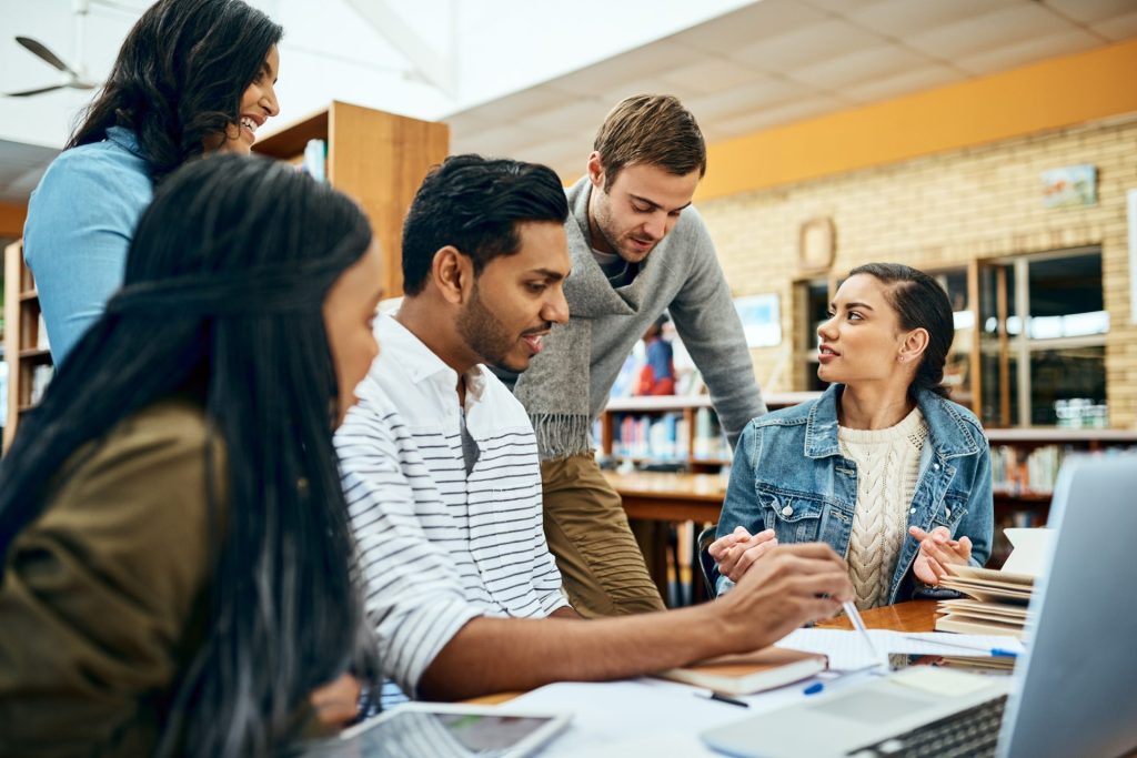 Group of 5 students working together in library